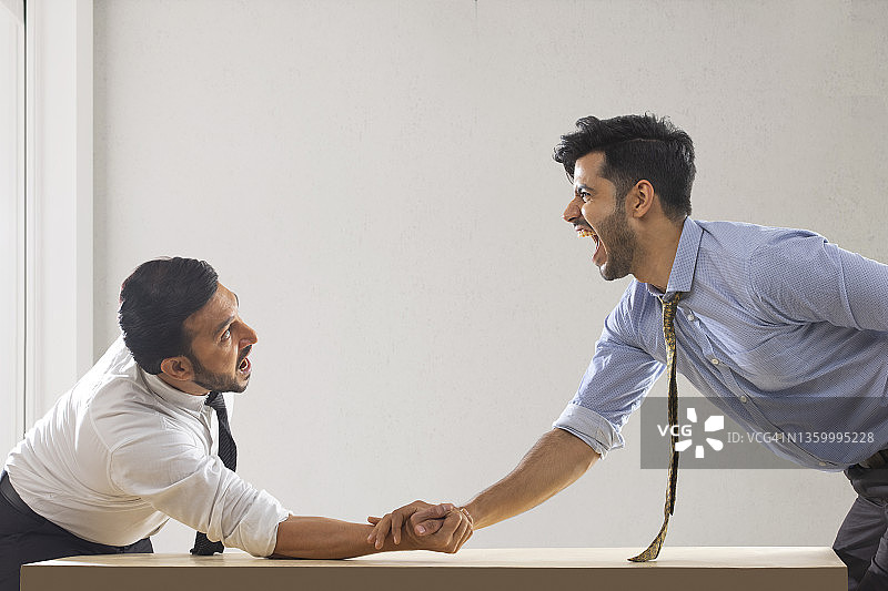 身着正装的企业员工扳手腕比赛，其中一人落败图片素材