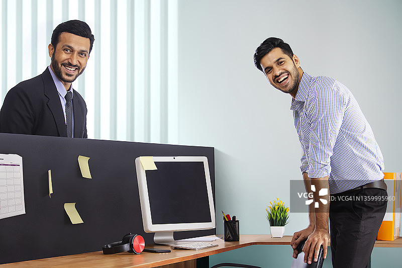 身着正装的公司员工在办公桌前微笑站立图片素材