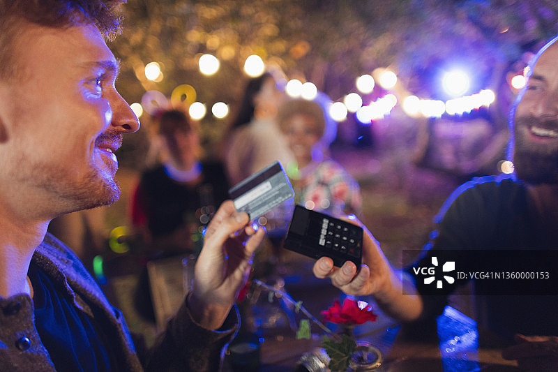 男人在聚会上用信用卡支付酒保图片素材