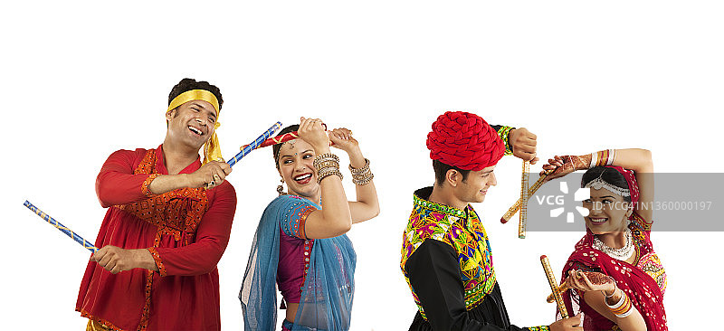 身着民族服装的印度夫妇跳着格尔巴舞，手持丹迪亚棍。图片素材