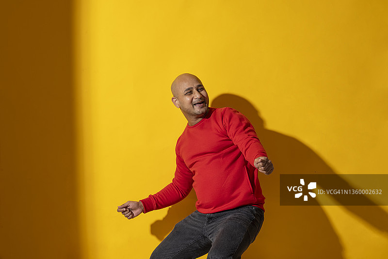 在纯色背景前跳舞的光头男人图片素材