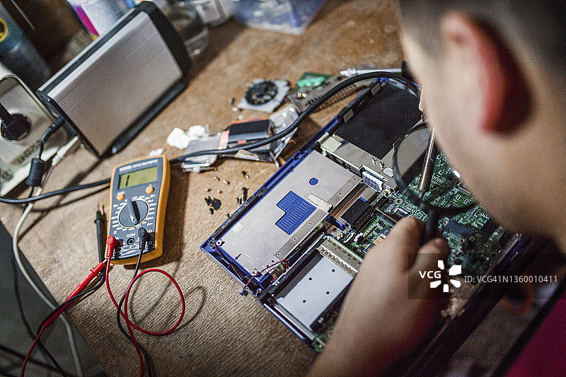 专家男人在他的办公室焊接电路板图片素材