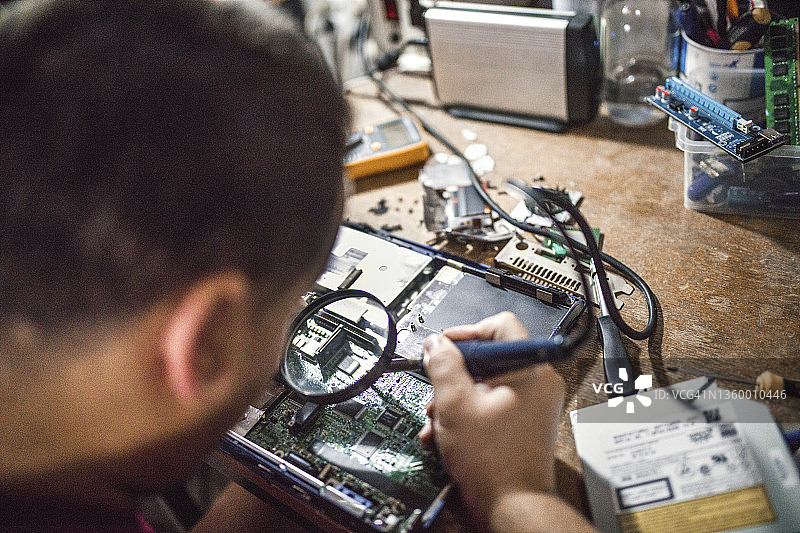 专家男人在他的办公室焊接电路板图片素材