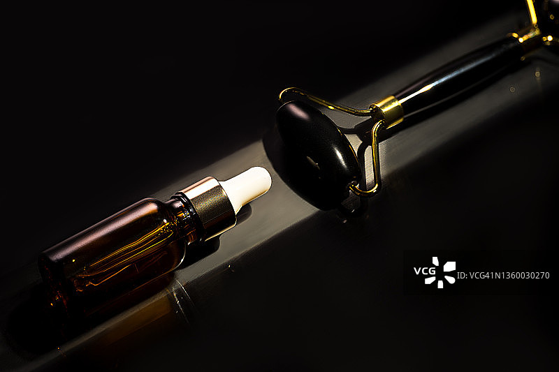 面部按摩美容产品，面部精华液和天然黑玉滚轮提拉按摩器图片素材