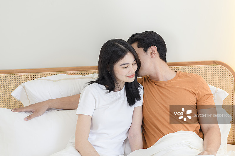 男子在床上对着女人的耳朵说话图片素材