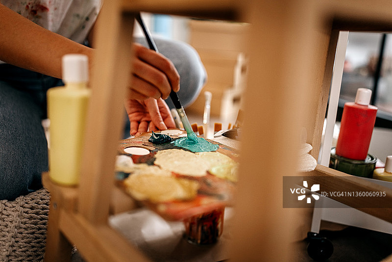 年轻女艺术家在调色板上调色图片素材