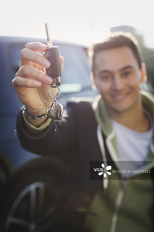 手持新车钥匙的快乐年轻男子肖像图片素材