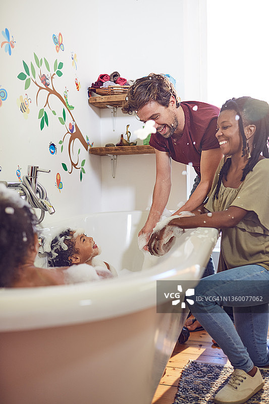 快乐的父母给女儿洗泡泡浴图片素材