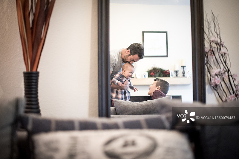 在苏格兰边境梅尔罗斯，年轻的父亲抱着女儿亲吻额头，和十几岁的儿子在圣诞节期间一起欢笑。图片素材