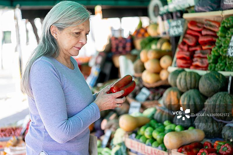 在农贸市场挑选红柿子椒的拉丁美洲老年妇女图片素材