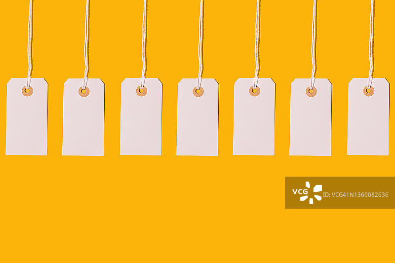 黄色背景上的七个白色纸板价格标签图片素材