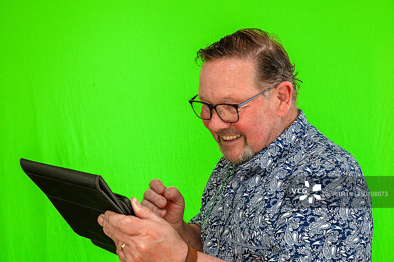 老年男人使用iPad联系家人朋友图片素材