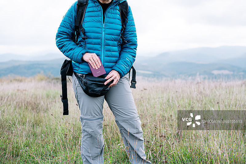 白天在山坡上将钱包放入腰包的背包客图片素材