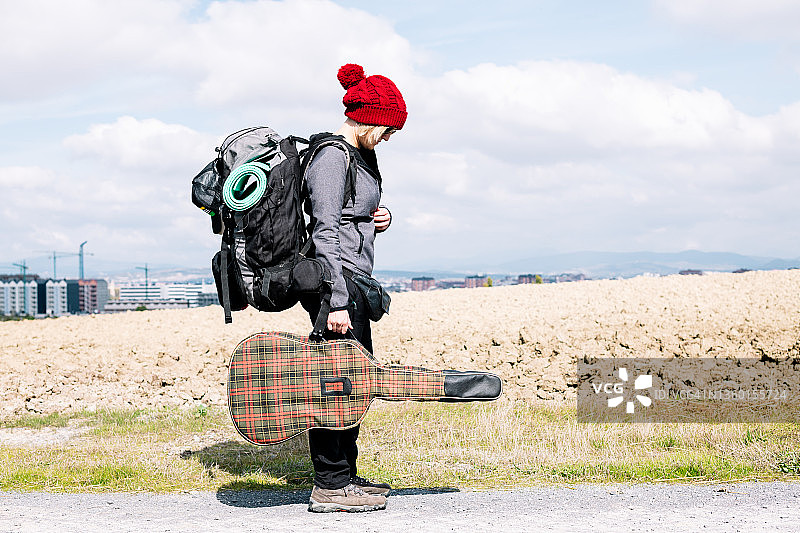 女人背着背包，带着吉他在路上图片素材