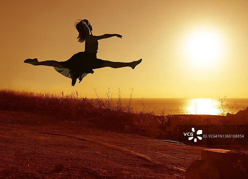 马耳他日落时分，舞者在空中劈叉的剪影图片素材