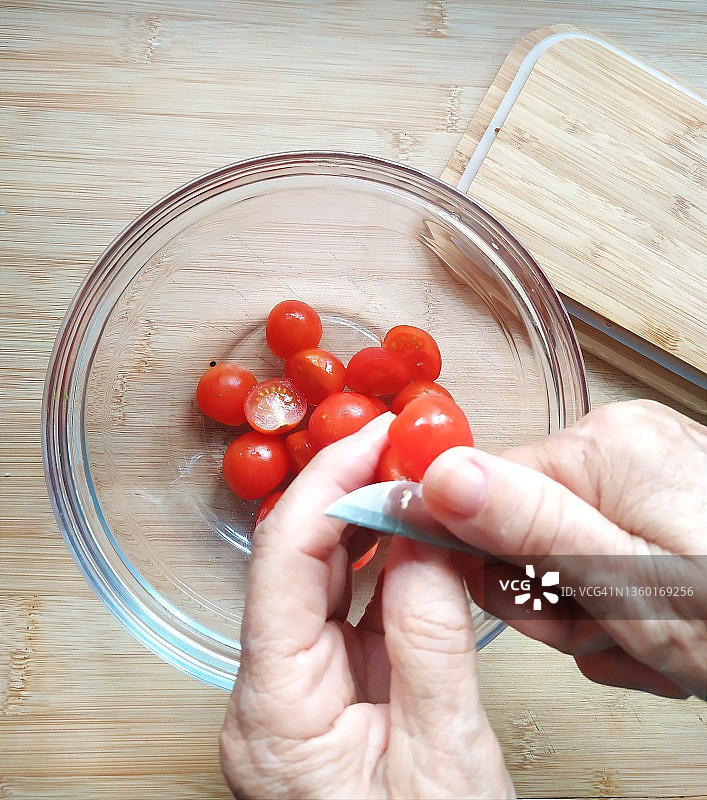 女人切半圣女果的特写图片素材