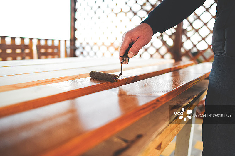 男子给天然木板刷清漆图片素材