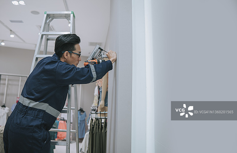 中国男子在服装店安装监控摄像头图片素材