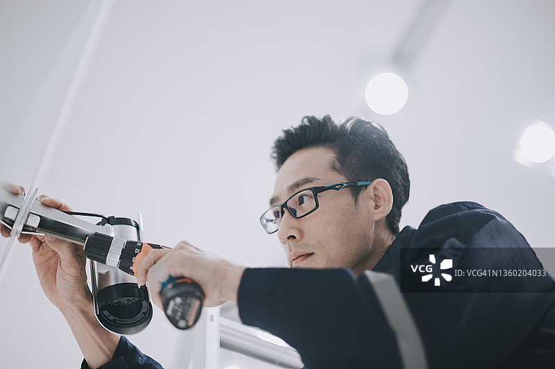 中国男子在服装店安装监控摄像头图片素材