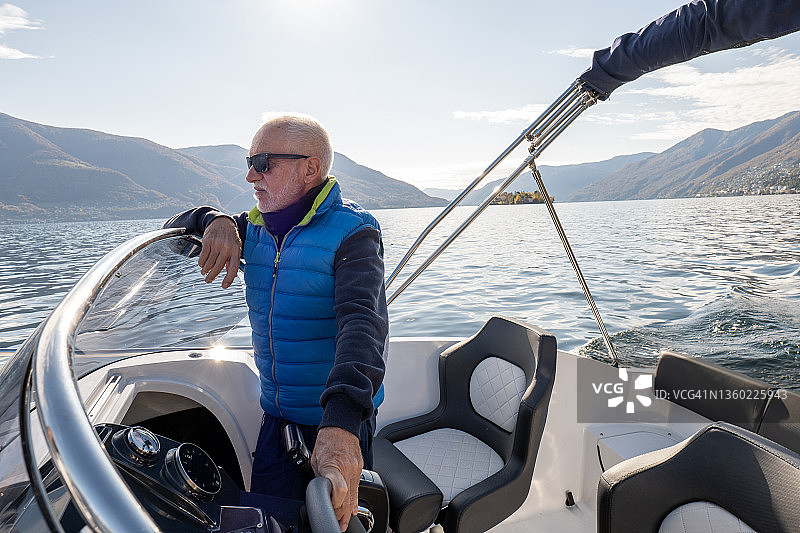 在平静的湖面上驾驶船只的中年男人图片素材