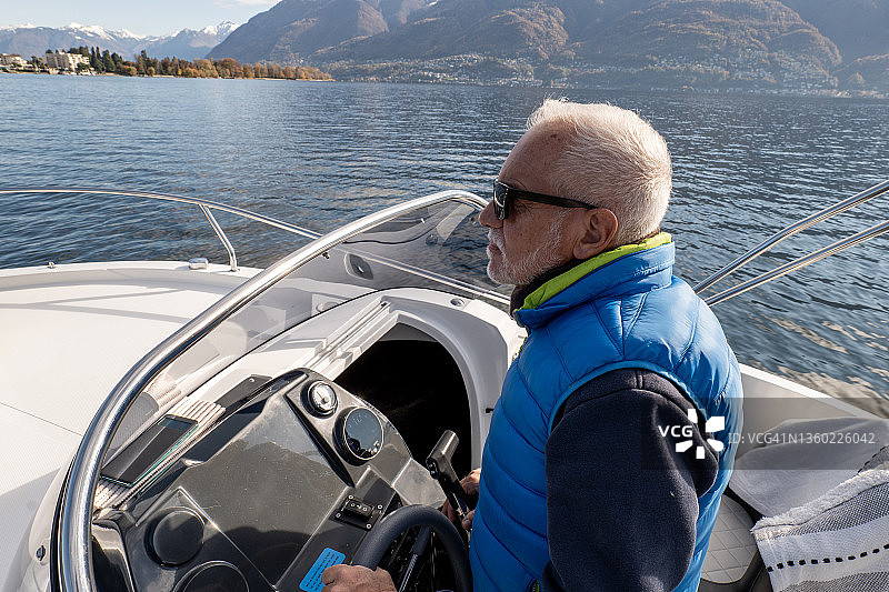 在平静的湖面上驾驶船只的中年男人图片素材