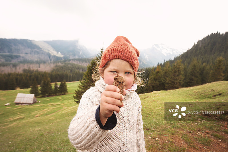 在山上展示捡到的松果的女孩图片素材