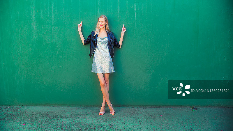 在绿色墙壁前摆姿势的女人，对着镜头调情图片素材