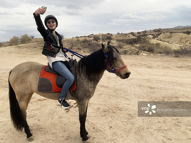 女人骑马用智能手机自拍图片素材