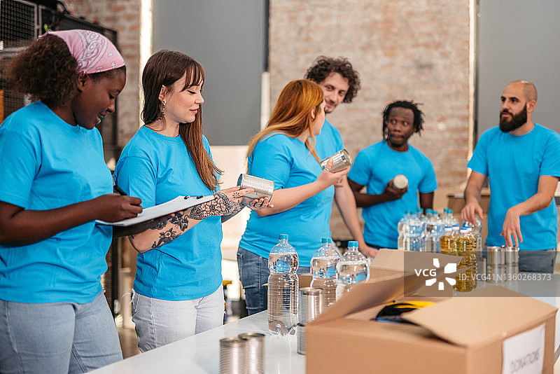 志愿者在捐赠中心整理水、油和罐头图片素材