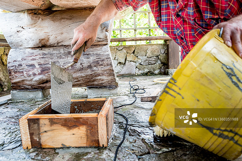 男人在房屋露台上用水泥砂浆建造新的户外桌子图片素材