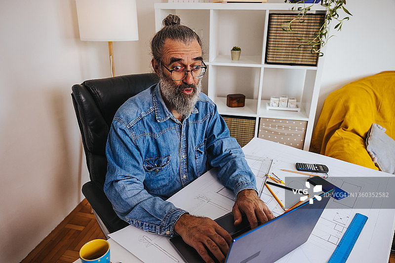 在家办公时进行视频通话的成熟男性建筑师图片素材