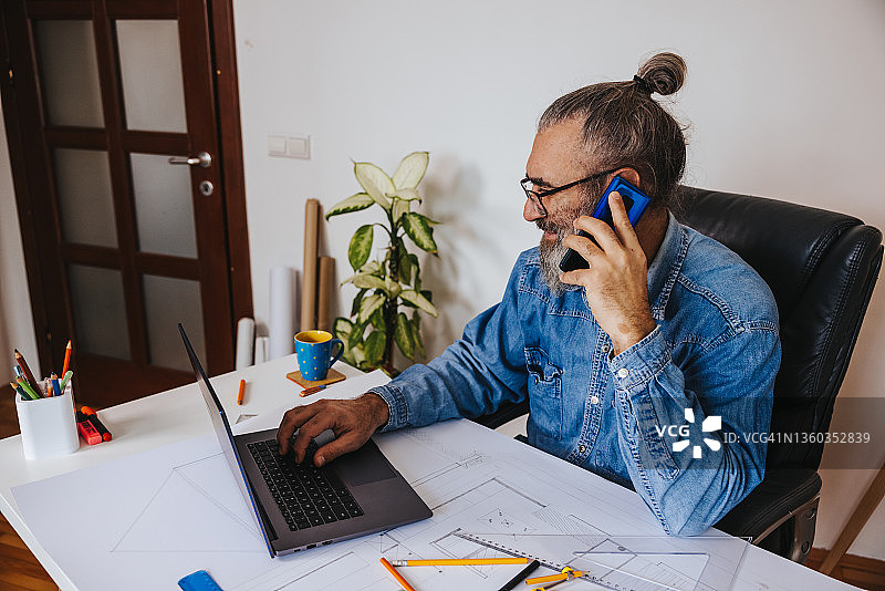 在工作室里使用手机的满意建筑师图片素材