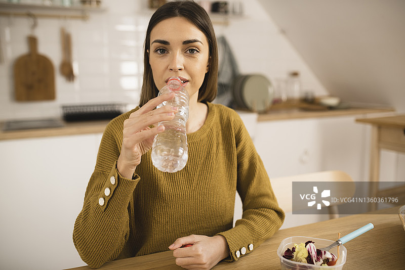 年轻女性吃沙拉时喝水的肖像图片素材