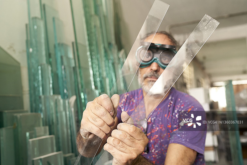 在玻璃工厂检查玻璃的老年男人图片素材