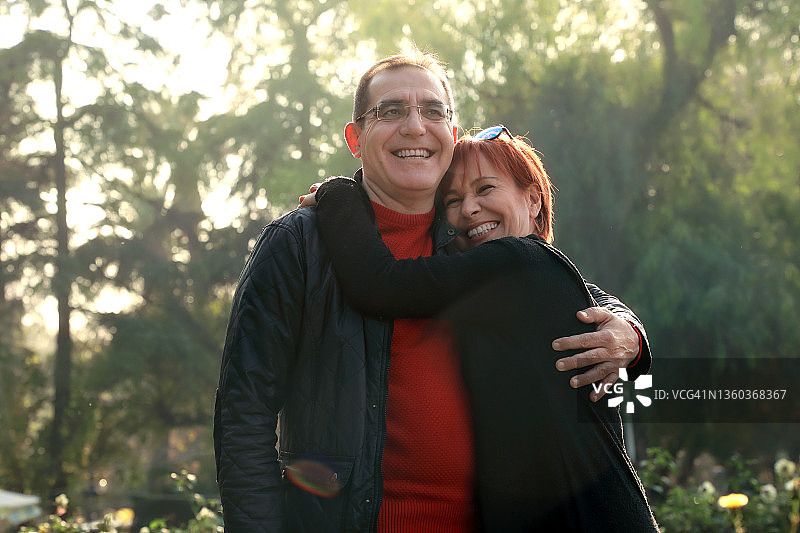 户外人像：在阳光明媚的绿色花园中的中年已婚白人夫妇图片素材