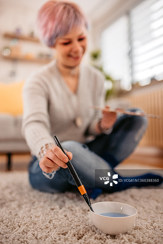 女艺术家在碗里用水清洗画笔图片素材