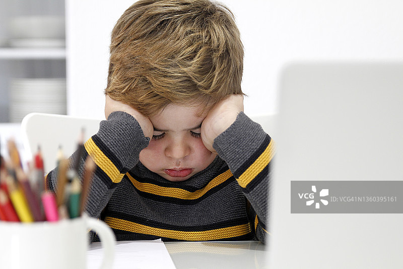 疲惫的男孩做作业特写图片素材