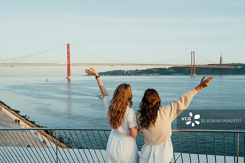 两个女人在吊桥边欣赏河景并挥手图片素材