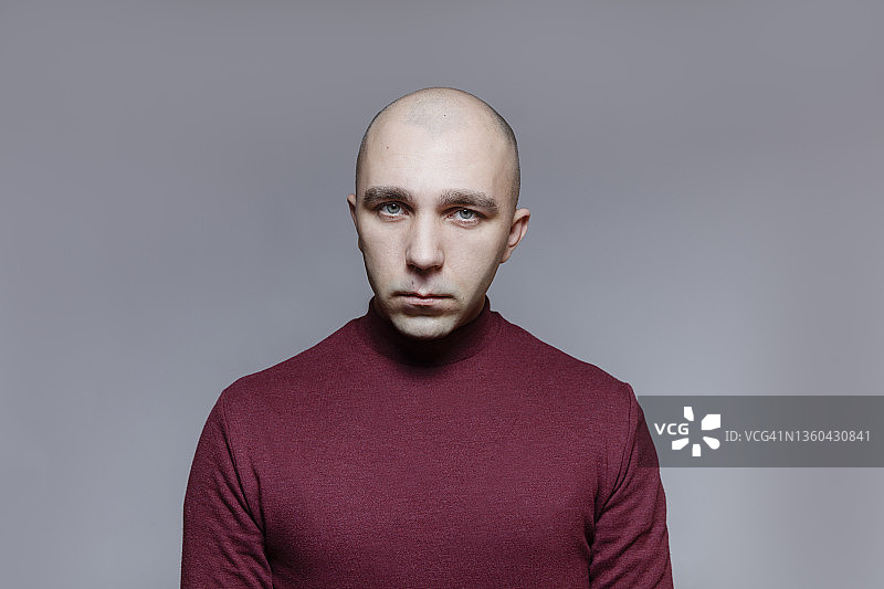 灰色工作室背景中表情严肃的光头男人图片素材
