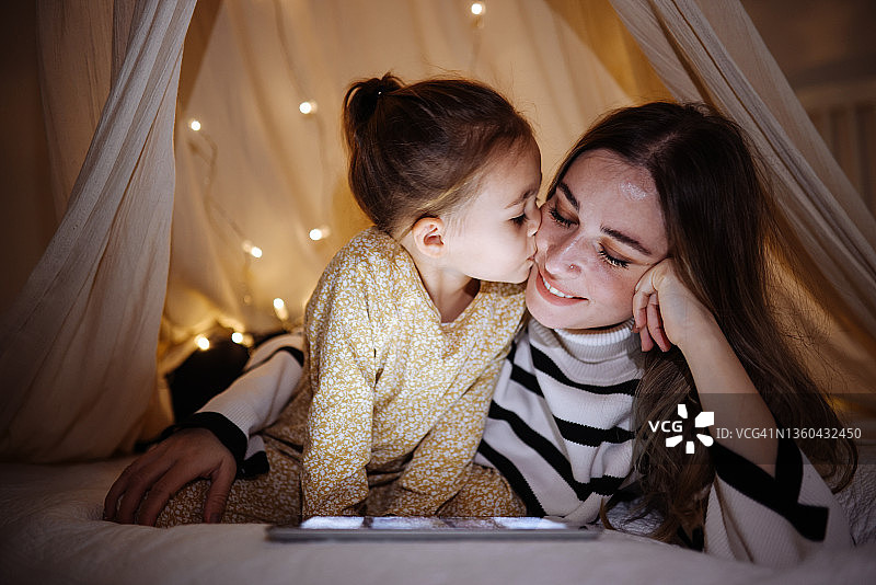 母女在床上帐篷里一起看平板电脑图片素材