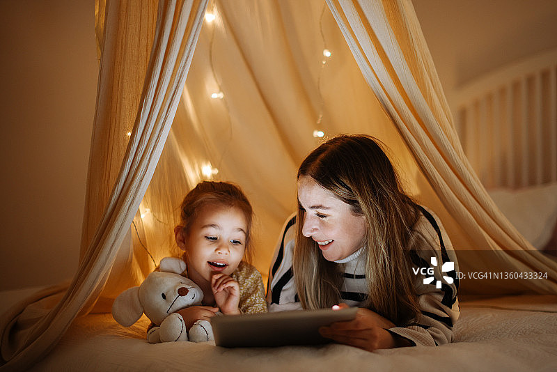 母女在床上帐篷里一起看平板电脑图片素材