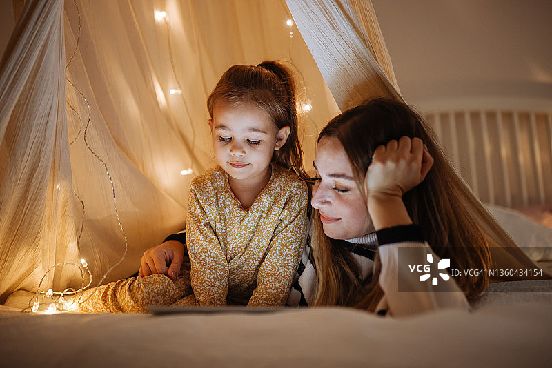 母女在床上帐篷里一起看平板电脑图片素材