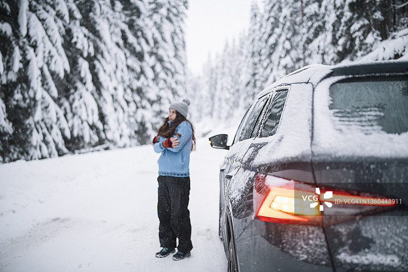 汽车抛锚后，女子在雪地路上等待救援图片素材