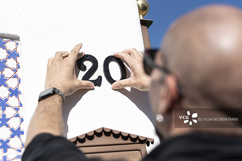 男人安装他即将居住的房屋号码：二十图片素材