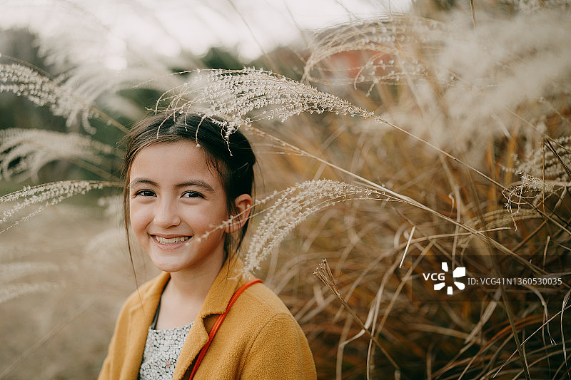 在东京秋季的芒草丛中的可爱年轻女孩图片素材