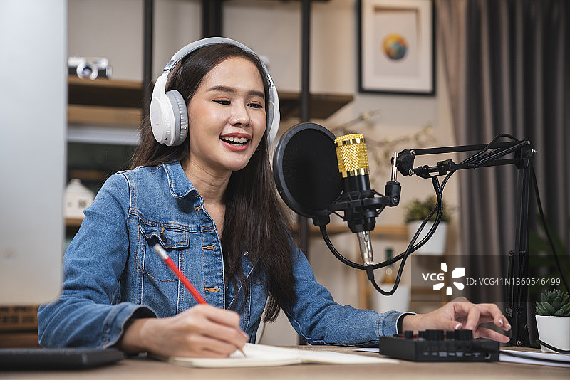 戴着黑色耳机在家录制播客的年轻女子图片素材