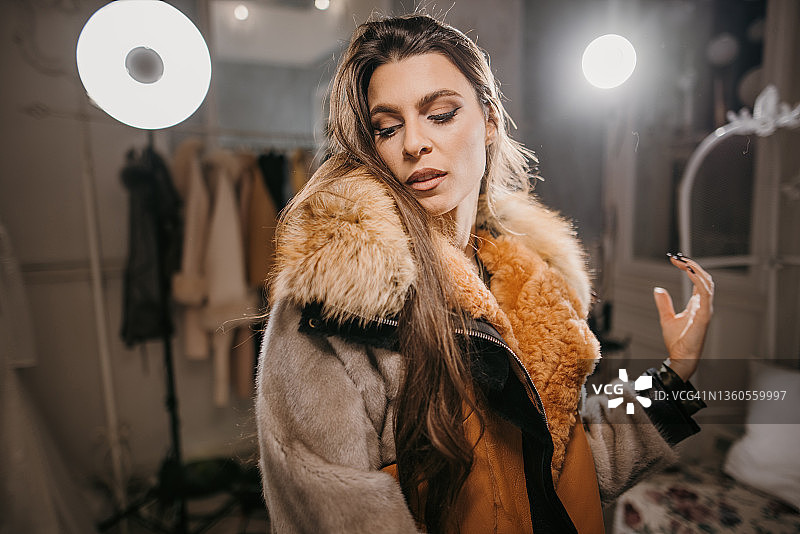 身穿毛皮夹克的女人在服装店摆姿势图片素材