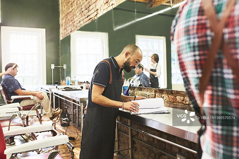 男理发师在理发店查看日程图片素材