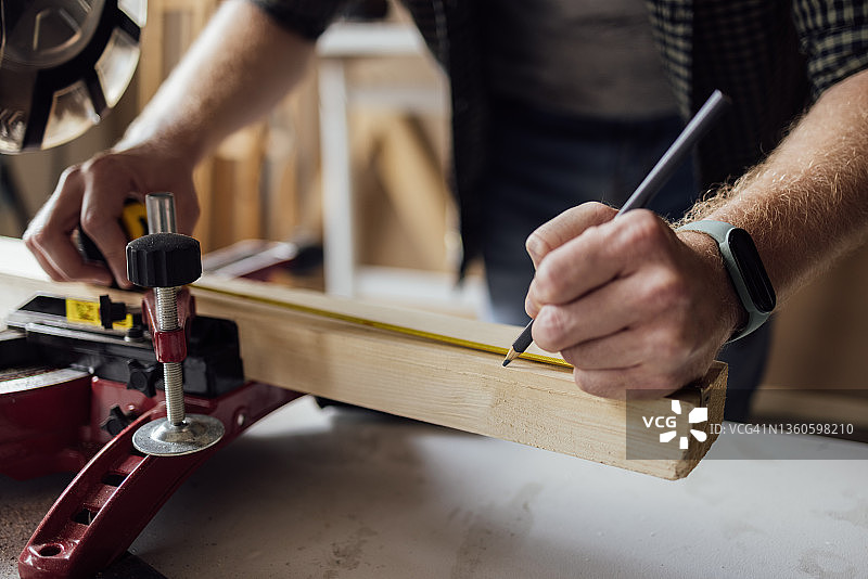 车间里测量木材的匿名木匠图片素材