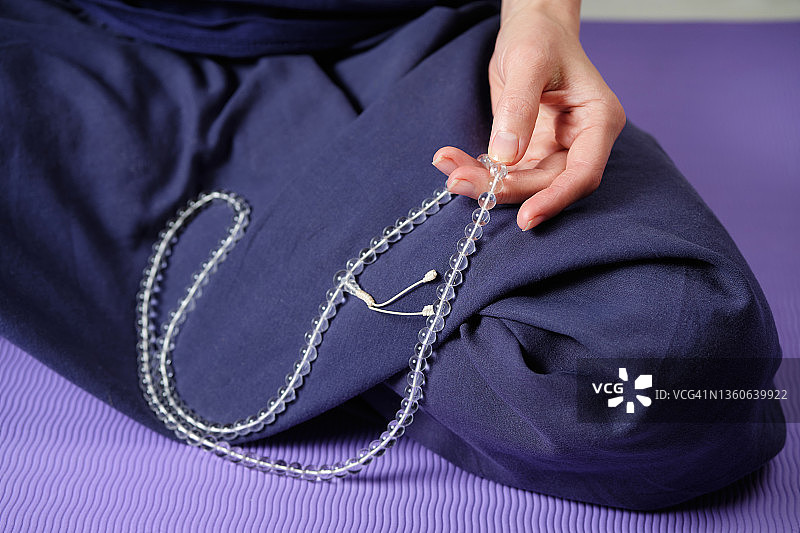 年轻女人手中的透明水晶念珠，她在做瑜伽，女人的手触摸着念珠，宗教信仰象征图片素材